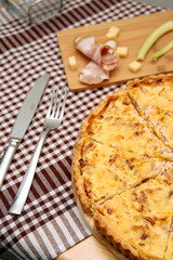Savory quiche with cheese and ham on checkered cloth in rustic setting
