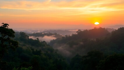 Fototapeta premium A scenic view of a sunrise over misty mountains with trees and an orange and yellow sky at dawn time