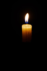 Close-up single candle burning on dark black background