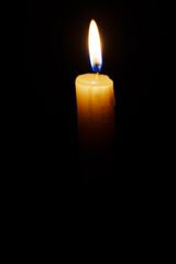 Close-up single candle burning on dark black background