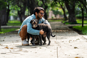 Man hugging his two mixed breed dogs in park