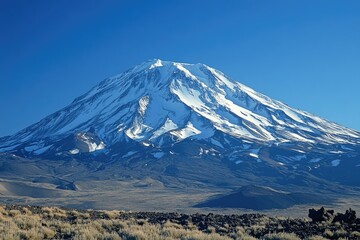Majestic snow-capped mountain peak under a clear blue sky, showcasing its immense size and grandeur.