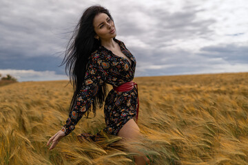 beautiful brunette woman stands gracefully in a lush wheat field, her long hair flowing in the wind...