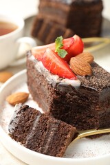 Piece of delicious chocolate cake with strawberry and almonds on table, closeup