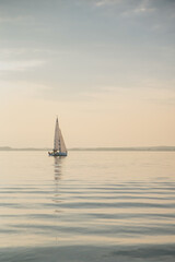 Obraz premium A sailboat on the river near the ocean - a calm, sunny day