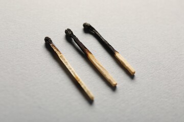 Burnt matches on grey background, closeup view