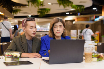 Gender diverse coworker business team eating salad and working digitally