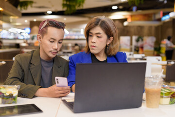 Gender diverse coworker business team eating salad and working digitally