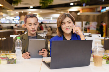 Gender diverse coworker business team eating salad and working digitally
