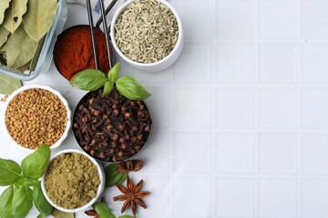 Different aromatic spices on white tiled table, flat lay. Space for text