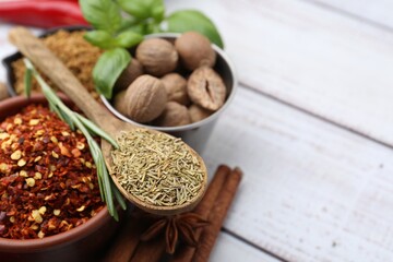 Different aromatic spices on white wooden table, closeup. Space for text