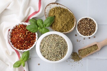 Different aromatic spices on white tiled table, flat lay