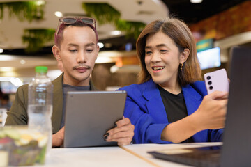 Gender diverse coworker business team eating salad and working digitally