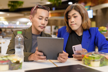 Gender diverse coworker business team eating salad and working digitally