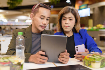 Gender diverse coworker business team eating salad and working digitally