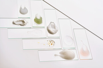 Texture samples of various cosmetic products on a gray background.
