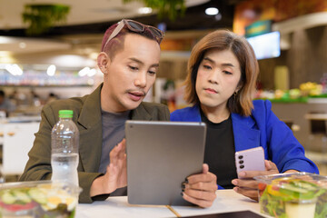 Gender diverse coworker business team eating salad and working digitally