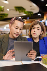 Gender diverse coworker business team eating salad and working digitally