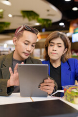 Gender diverse coworker business team eating salad and working digitally