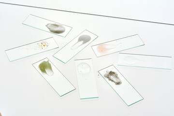 Various cosmetic products on slides on a gray background.
