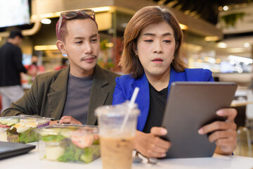 Gender diverse coworker business team eating salad and working digitally