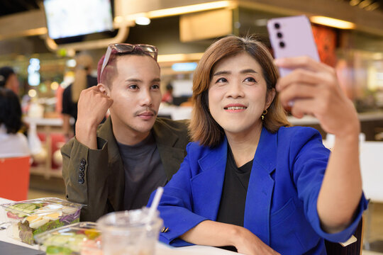 Gender diverse coworker business team eating salad and working digitally taking selfie with phone - Powered by Adobe