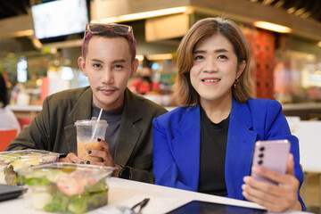 Gender diverse coworker business team eating salad and working digitally