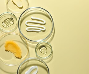 Different cosmetic products in Petri dishes on pale yellow background, flat lay. Space for text