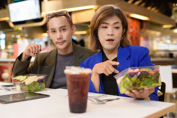 Gender diverse coworker business team eating salad and working digitally
