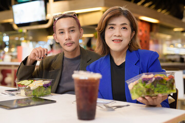 Gender diverse coworker business team eating salad and working digitally