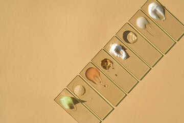 Various cosmetic textures on slides in a row on a beige background.