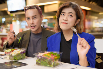 Naklejka premium Gender diverse coworker business team eating salad and working digitally