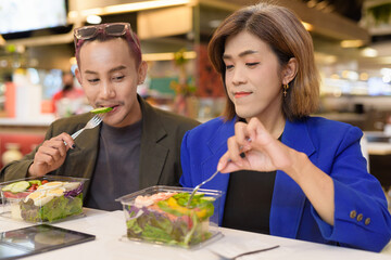 Gender diverse coworker business team eating salad and working digitally