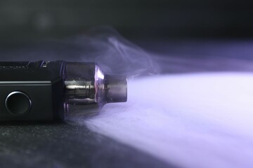 Modern electronic smoking device on black table, closeup. Space for text