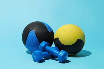 Medicine balls and dumbbells on light blue background