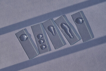 Samples of serum or micellar water on slides on a blue background with streaks of shadows.