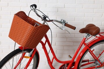 Red bicycle with basket near white brick wall indoors, closeup