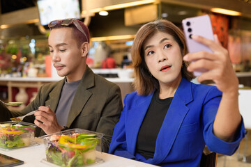 Gender diverse coworker business team eating salad and working digitally