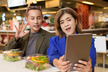 Gender diverse coworker business team eating salad and working digitally