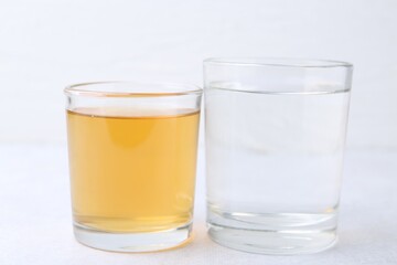 Glasses with clean and dirty water on light table, closeup