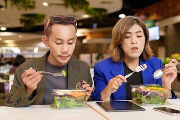 Gender diverse coworker business team eating salad and working digitally