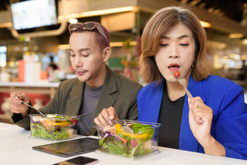 Gender diverse coworker business team eating salad and working digitally