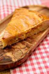 Savory pumpkin pie slice on wooden tray with checkered tablecloth