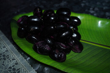 Smooth‑skinned, deep purple‑black round fruit with soft red or yellow flesh, sweet‑tart flavor, richly antioxidant and fiber‑packed