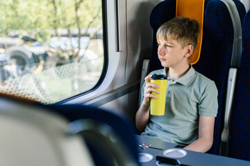 Teenage boy drinking from reusable mug on train