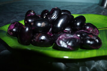 Smooth‑skinned, deep purple‑black round fruit with soft red or yellow flesh, sweet‑tart flavor, richly antioxidant and fiber‑packed