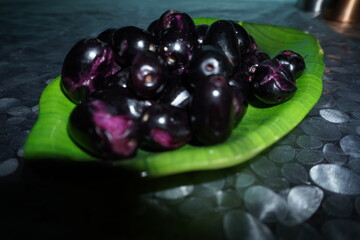 Smooth‑skinned, deep purple‑black round fruit with soft red or yellow flesh, sweet‑tart flavor, richly antioxidant and fiber‑packed