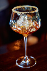 Elegant cocktail glass with ice and sugar rim on dark wood surface
