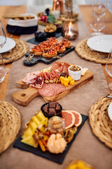 Elegant charcuterie board with assorted meats, cheeses, fruits, and nuts on wooden and slate platters