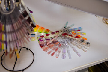 Palette for nail polish on white table. Nude, pastel nail polish samples. Soft focus. The mess at the manicure master's workplace